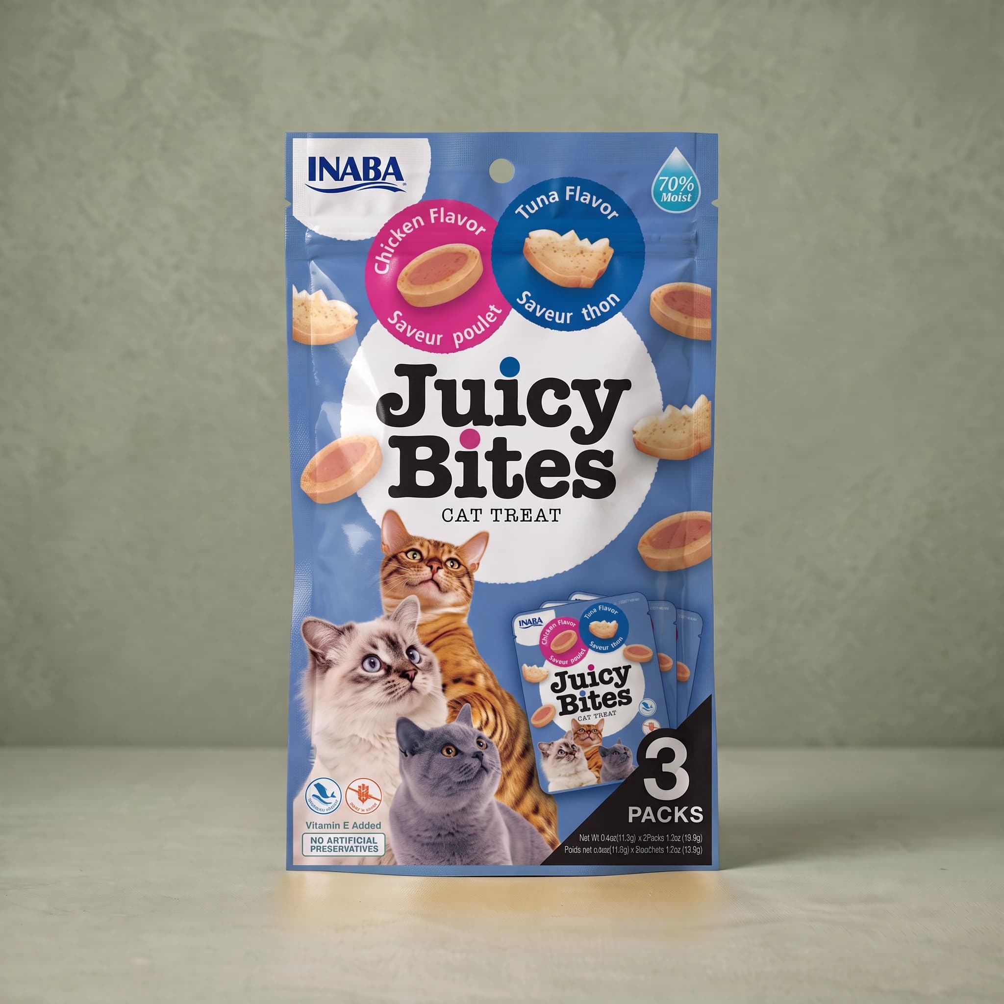 Blue INABA Juicy Bites cat treat pouch in the Chicken and Tuna flavours, with a pink 'Chicken Flavor' roundel showing an oval treat and a blue 'Tuna Flavor' roundel showing a fish-tail-shaped treat, a '70% Moist' droplet flash, photographs of three cats, and a '3 PACKS' panel.