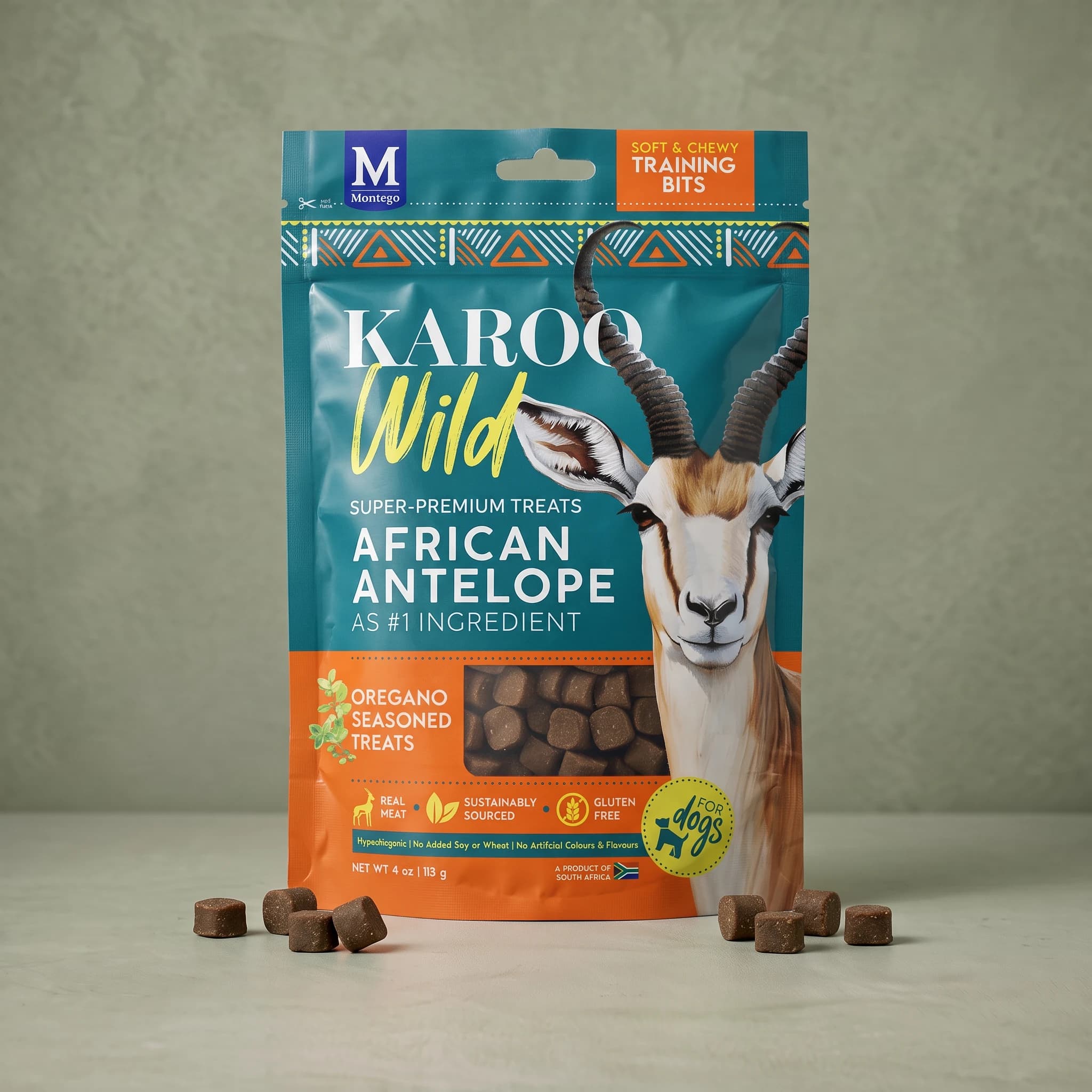The same teal and orange Karoo Wild Oregano Training Bits pouch standing upright against a plain sage green background, with small round pellet treats scattered symmetrically on either side at its base.