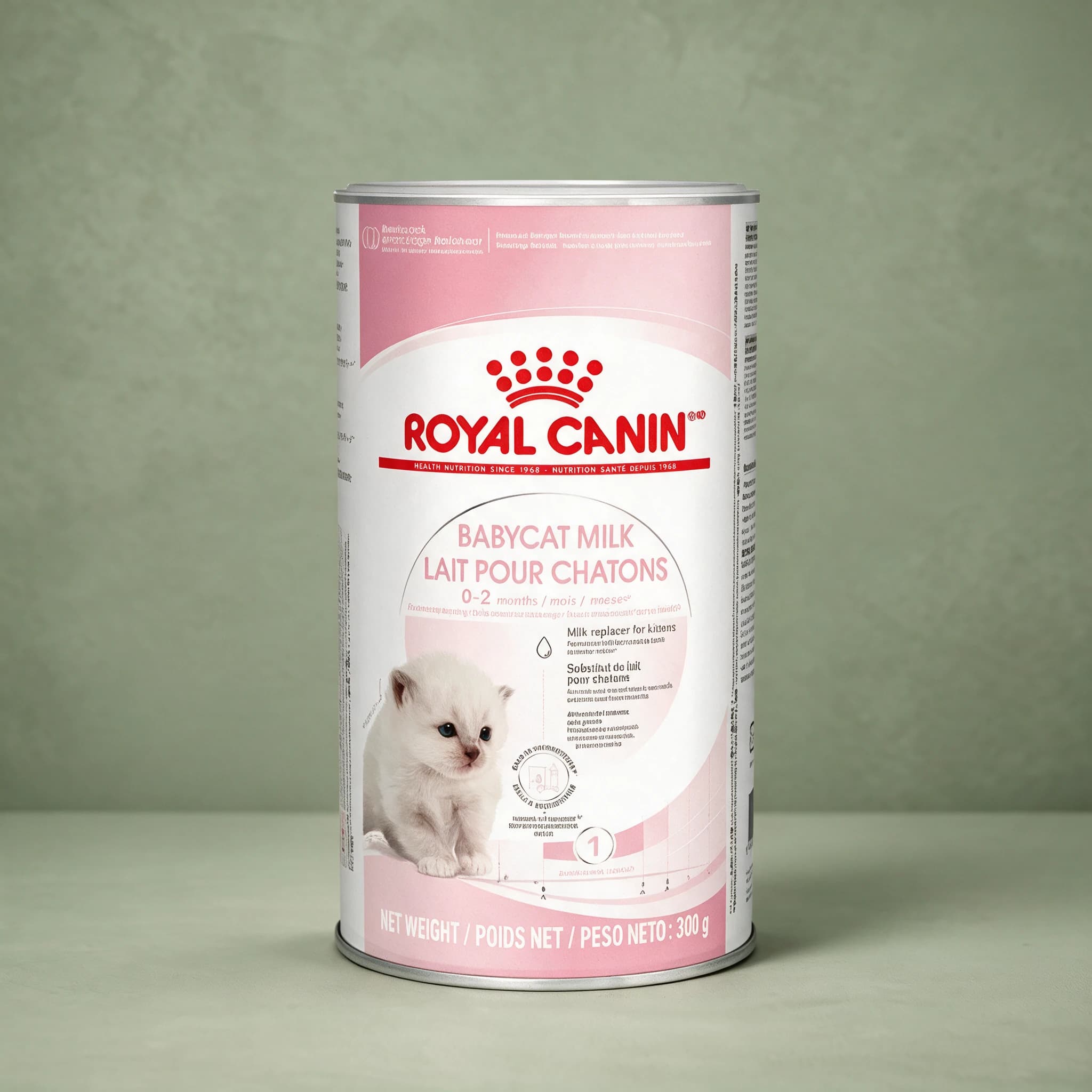 The pink and white Royal Canin Babycat Milk tin with the red crown logo and a kitten illustration, photographed upright against a plain sage green studio background.