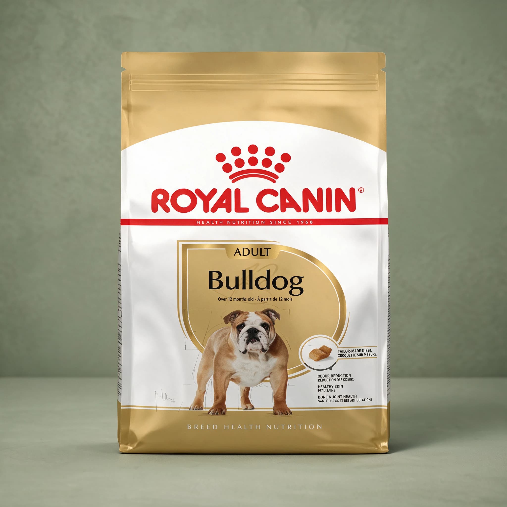 A fawn and white Royal Canin bag printed with a Bulldog illustration and labeled "Bulldog Adult," standing upright against a sage green studio background.