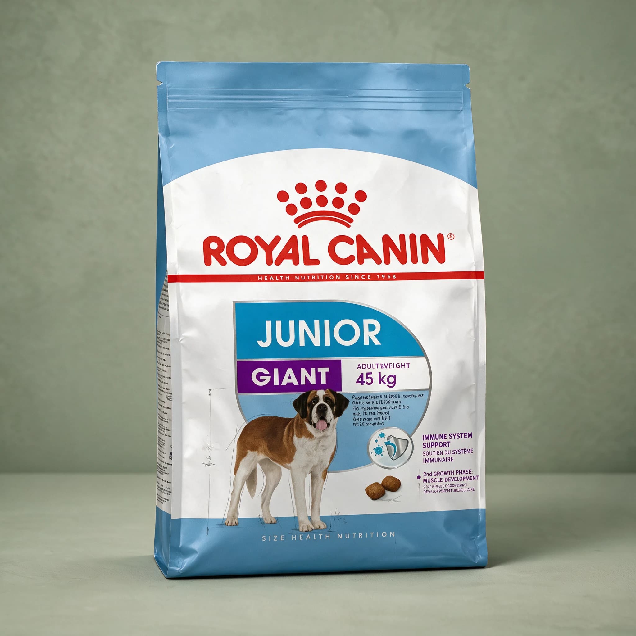 The white and blue Royal Canin Giant Junior dry dog food bag, featuring an illustration of a large-breed puppy and "Junior" life-stage branding, photographed against a plain sage green studio background.
