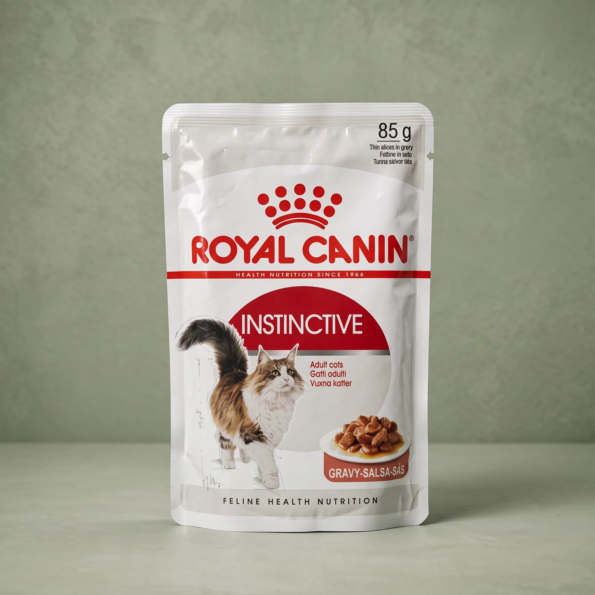 A single white and red Royal Canin Instinctive Adult Gravy wet cat food pouch, featuring a cat illustration, photographed against a plain sage green studio background.