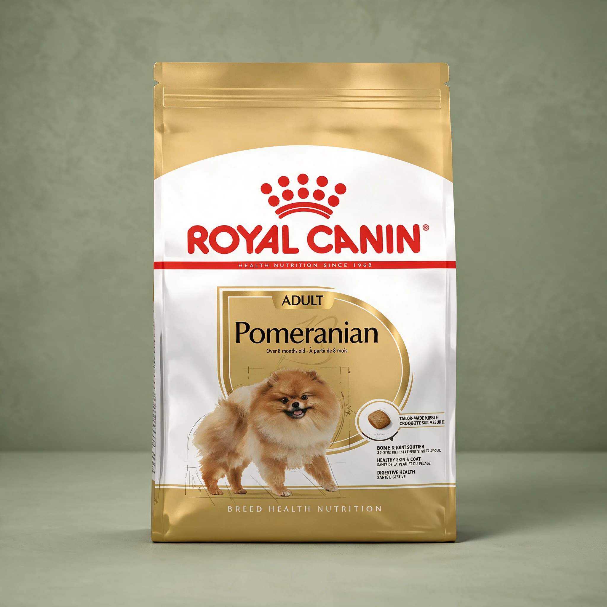 A gold and white Royal Canin bag printed with a Pomeranian illustration and labeled "Pomeranian Adult," standing upright against a sage green studio background.