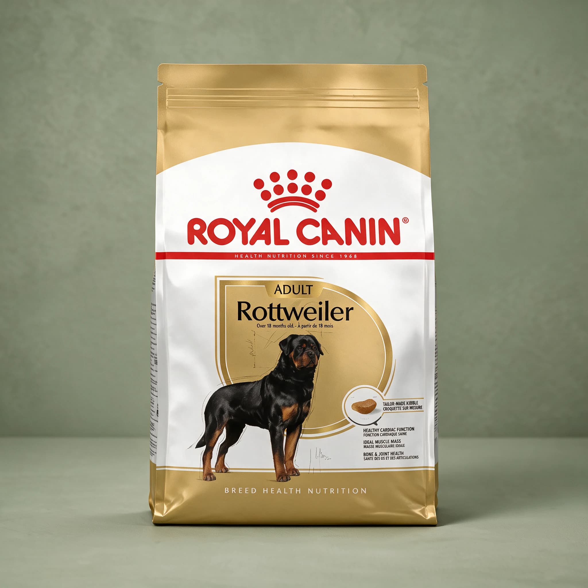 The gold and white Royal Canin Breed Health Nutrition bag labeled "Rottweiler Adult" with an illustration of a Rottweiler and callouts for healthy cardiac function, ideal muscle mass, and bone and joint health, photographed against a plain sage green studio background.