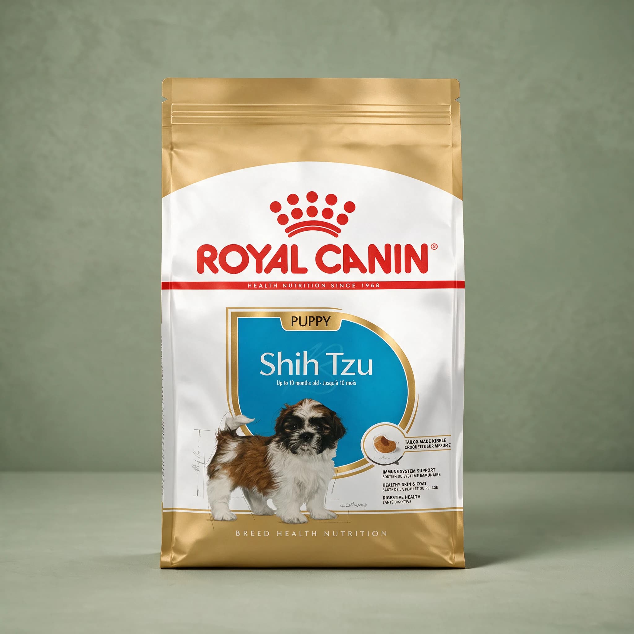 The gold and white Royal Canin Shih Tzu Puppy dry dog food bag, featuring an illustration of a brown-and-white Shih Tzu puppy and "Tailor-Made Kibble" callout, photographed against a plain sage green studio background.