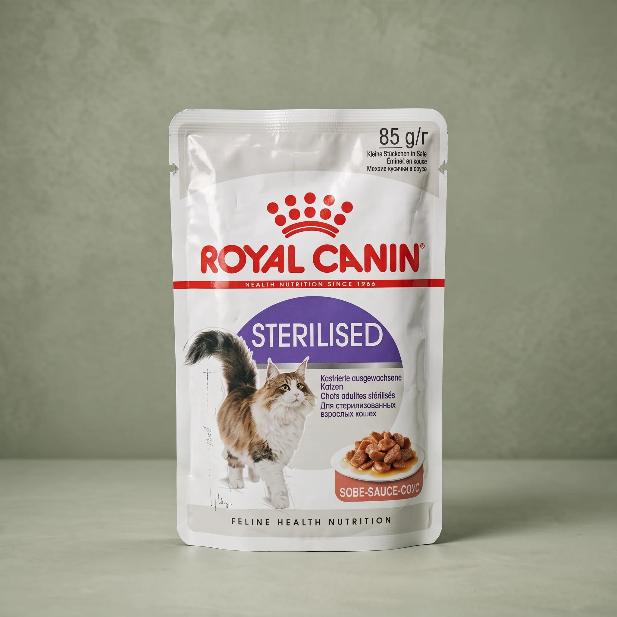 A Royal Canin Sterilised Adult wet cat food pouch with the red crown logo and an adult cat illustration, labeled "in gravy," standing upright against a plain sage green studio background.