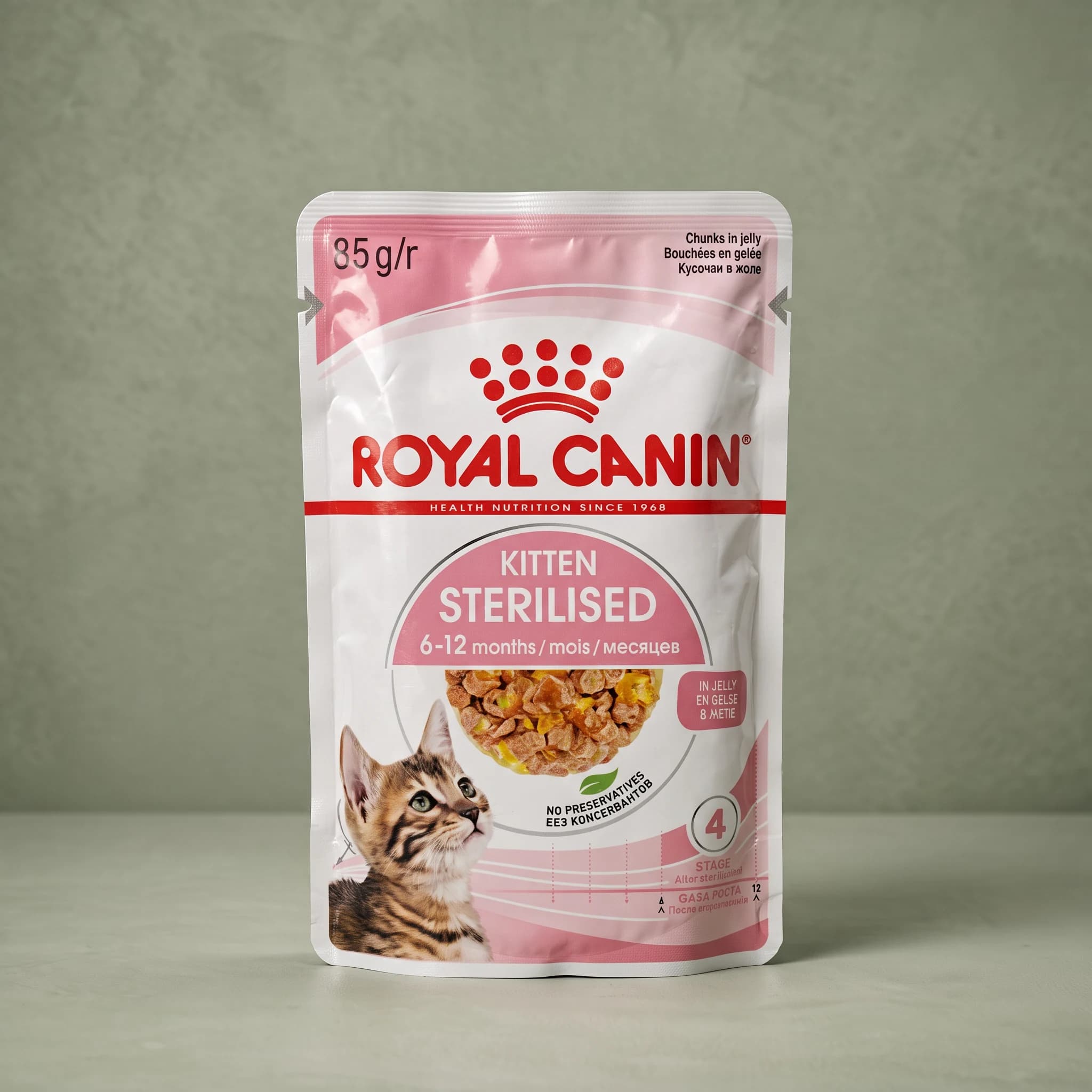 A Royal Canin Sterilised Kitten Jelly wet cat food pouch with a kitten illustration and jelly-coated chunks pictured on the label, against a plain sage green studio background.